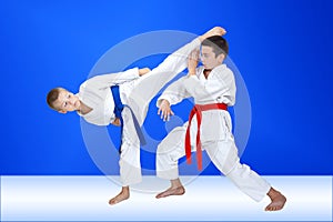 Boys in karategi are training a circular kick and block