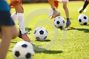 Boys kick football balls. Children attending outdoor soccer class. School children running and kicking balls