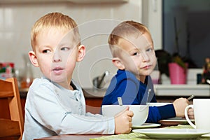 Boys kids children eating corn flakes breakfast meal at the table