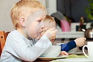 Boys kids children eating corn flakes breakfast meal at the table