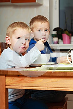 Boys kids children eating corn flakes breakfast meal at the table