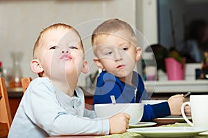 Boys kids children eating corn flakes breakfast meal at the table