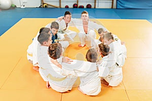 Boys in kimono sitting on the floor, judo training photo