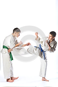 Boys in kimono during training karate exercises on white background