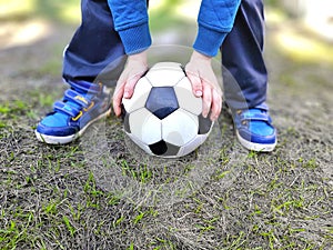 Boys legs and ball holding hands on green grass.