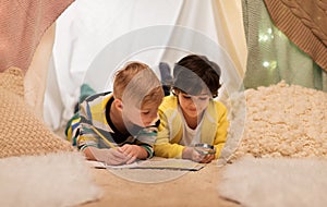 Boys with magnifier and map in kids tent at home