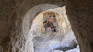 Boys pass through a passageway in the rock, then hide in the rock.