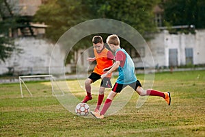 Boys payers wearing sport uniform playing soccer. Competition between players running and kicking football ball photo