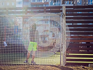 The boys play in the courtyard on a specially equipped football field on the background of apartment buildings