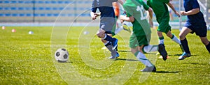 Boys play soccer match. Blue and green team on a sports field