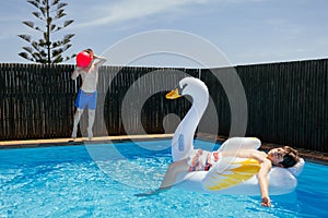 Boys playing ball and inflatable mattress in swimming pool