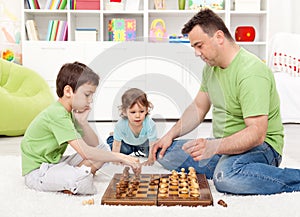 Boys playing chess with their father