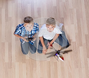 Boys playing with flying helicopter model at home using remote control