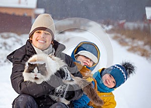 boys plays with a cat outdoors in winter