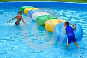 The boys in the pool in the summer. Children at the water Park. Water inflatable swimming laps in the pool.
