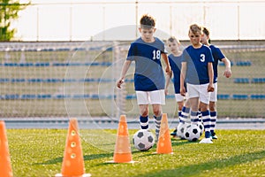 Boys practice football dribbling in a field