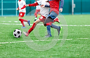 Boys in red and white sportswear plays soccer on green grass field. Youth football game. Children sport competition