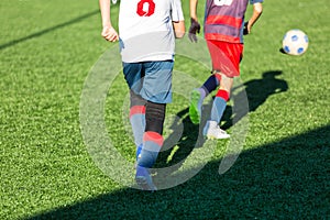 Boys in red white sportswear running on soccer field. Young footballers dribble and kick football ball in game. Training