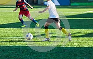 Boys in red white sportswear running on soccer field. Young footballers dribble and kick football ball in game. Training