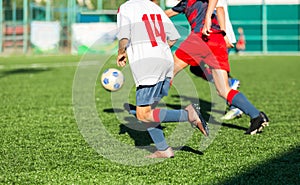 Boys in red white sportswear running on soccer field. Young footballers dribble and kick football ball in game. Training,