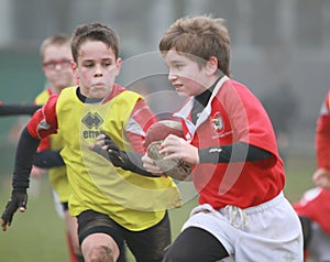 Boys with red/yellow jacket play rugby