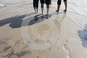 Boys with rolled up paint on the wet sandy beach footprint on wet sand and feet