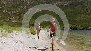 Boys running at the beach towards the camera