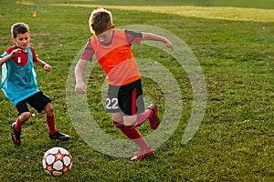 Boys running dribbling wearing sport uniform in team jersey and cleats. Kids play football on soccer field. Children