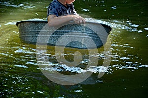 The boys sail on a boat made of old tin, tubs, a bucket, a barrel, a bowl, an oval-shaped flower pot. they fall on the river with