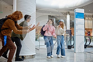 Boys scaring girls for joke, children spending time at shopping mall