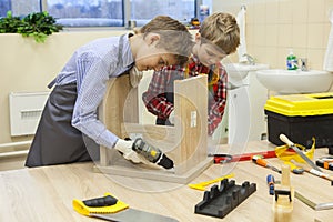 Boys with screwdrivers and drill repairing wooden stool