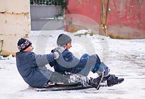 Boys sledding in a snowy . Children ski in the snow . The children were very happy and laughing . Two very happy caucasian kids