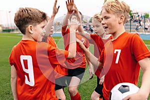 A boys soccer team celebrating a victory. Motivated children sports team rising hands up