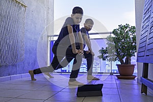 Boys with tablet computer doing sport exercises on balcony. Sport, healhty lifestyle, active leisure at home