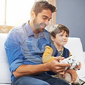 Boys and their toys. a father and his young son playing video games.