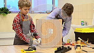 Boys tightening screws in wooden stool