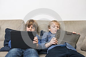 Boys Using Digital Tablets On Sofa