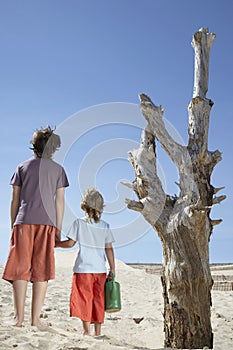 Boys With Watering Can Standing By Dead Tree