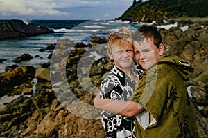 Boys wearing hooded towels after swimming mucking around on rocks at The Tanks tourist attraction at Forster, NSW Australia photo