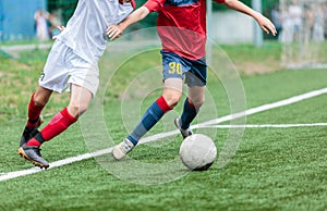 Boys in white and red sportswear plays football on field, dribbles ball. Young soccer players with ball on green grass. Training,