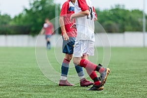 Boys in white and red sportswear plays football on field, dribbles ball. Young soccer players with ball on green grass. Training,