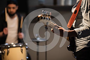 A boysband of guitarist, bassist, and drummer rehearse in their garage.