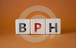 BPH - Benign Prostatic Hyperplasia symbol. Wooden cubes with word BPH. Beautiful orange background. Medical and BPH concept. Copy