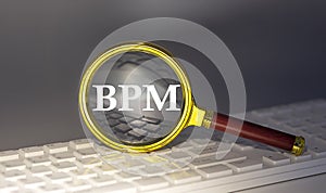 BPM text on magnifier on a keyboard, business concept