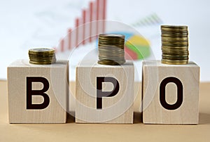 BPO - abbreviation on wooden balls on a background of coins and graphics