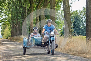 Cheerful couple on classic motor with sidecar at countryside, Netherlands