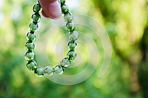 Bracelet on the background of nature. Bracelet from green beads on an elastic band. Decoration for girls.
