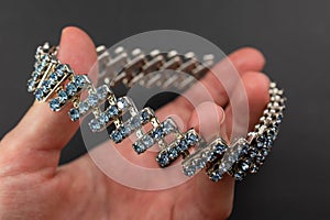 Bracelet with blue gemstones in hand on a black background