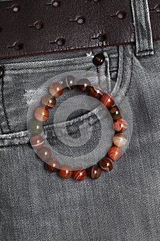 Bracelet made of agate stones on the hand close-up on the background of jeans