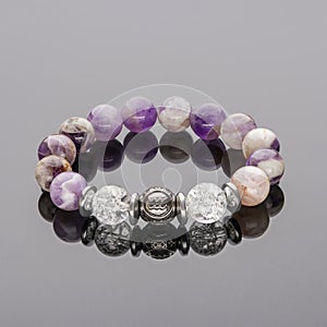 Bracelet made of amethyst and quartz,. Bracelet made of natural stones on the hand on a dark background with reflection